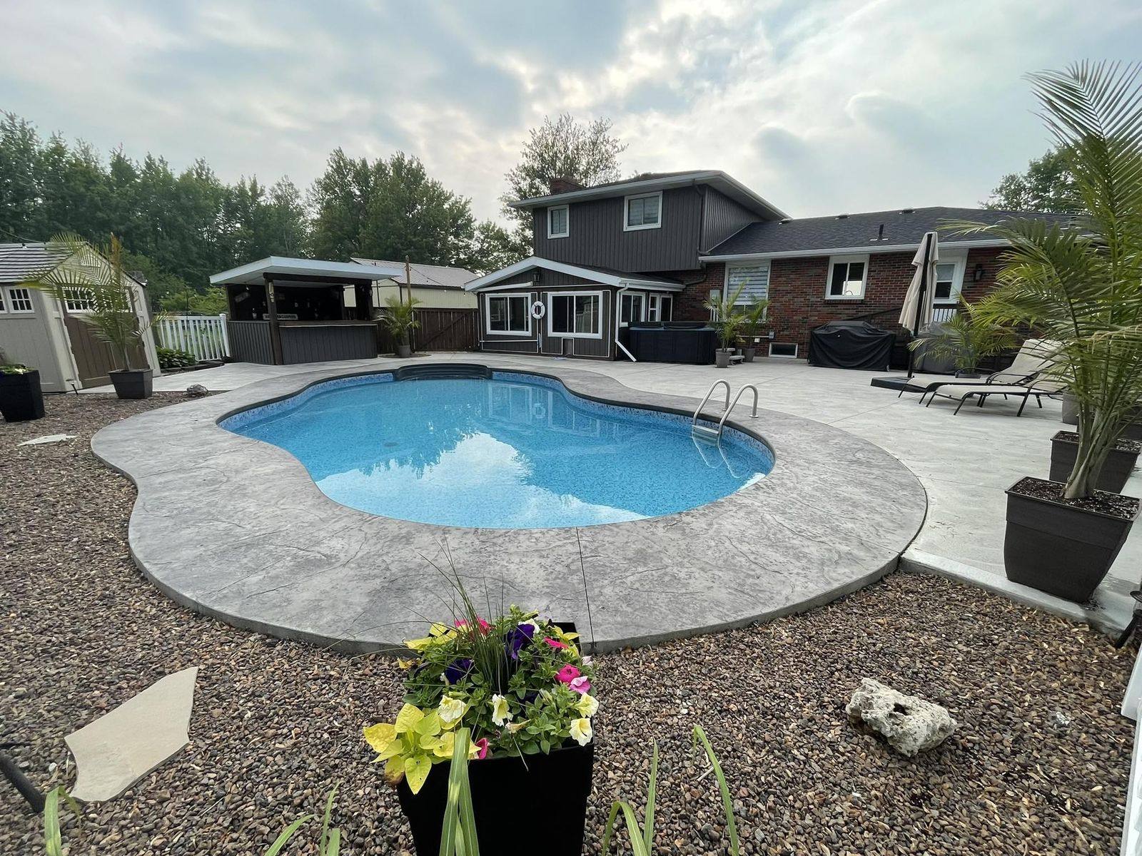 Backyard pool with new stamped-border concrete surround at dusk