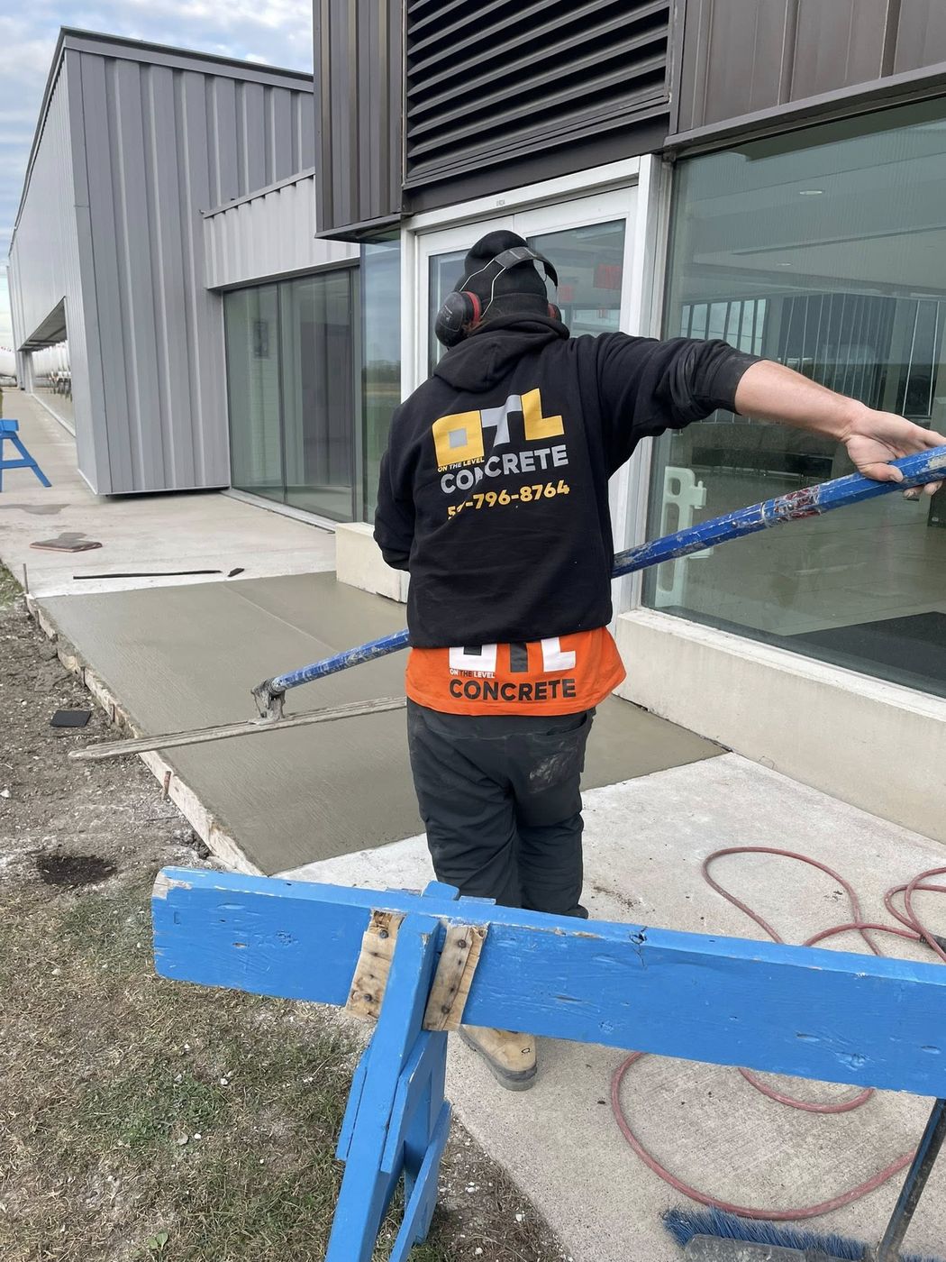 OTL branded crew screeding fresh concrete at a commercial building